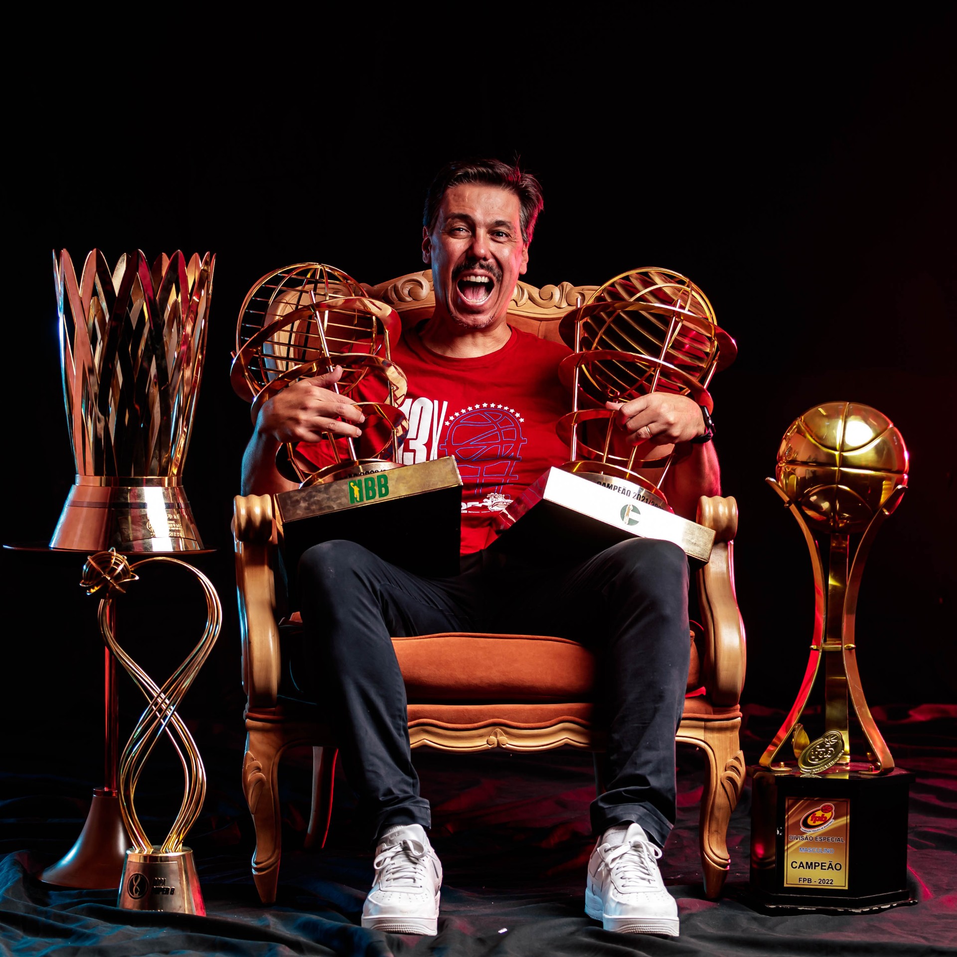 Técnico celebrando com troféus de campeonato