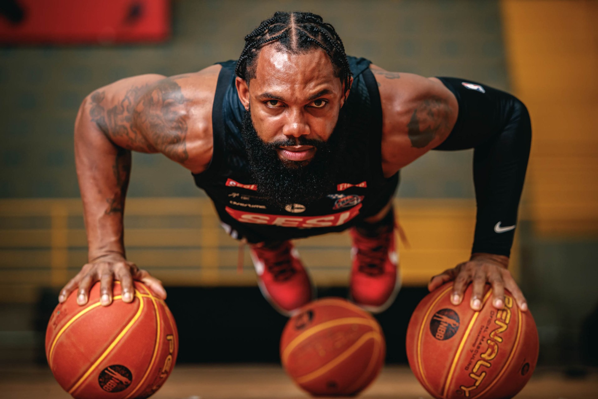 Atleta de basquete do SESI em posição de flexão com três bolas